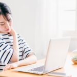デスクワークのやり過ぎで巻き肩姿勢で肩こりに悩む女性