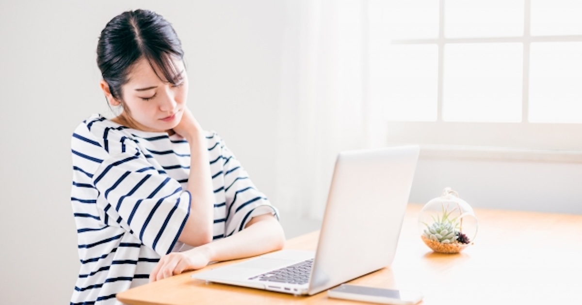デスクワークのやり過ぎで巻き肩姿勢で肩こりに悩む女性