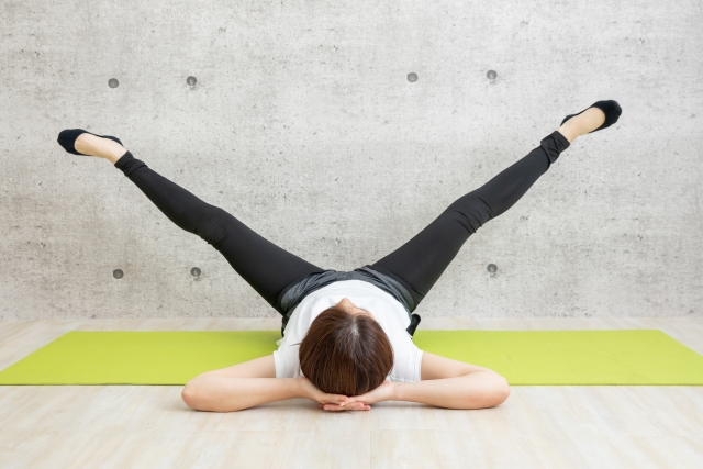 内ももの開脚ストレッチを壁を使って行っている女性